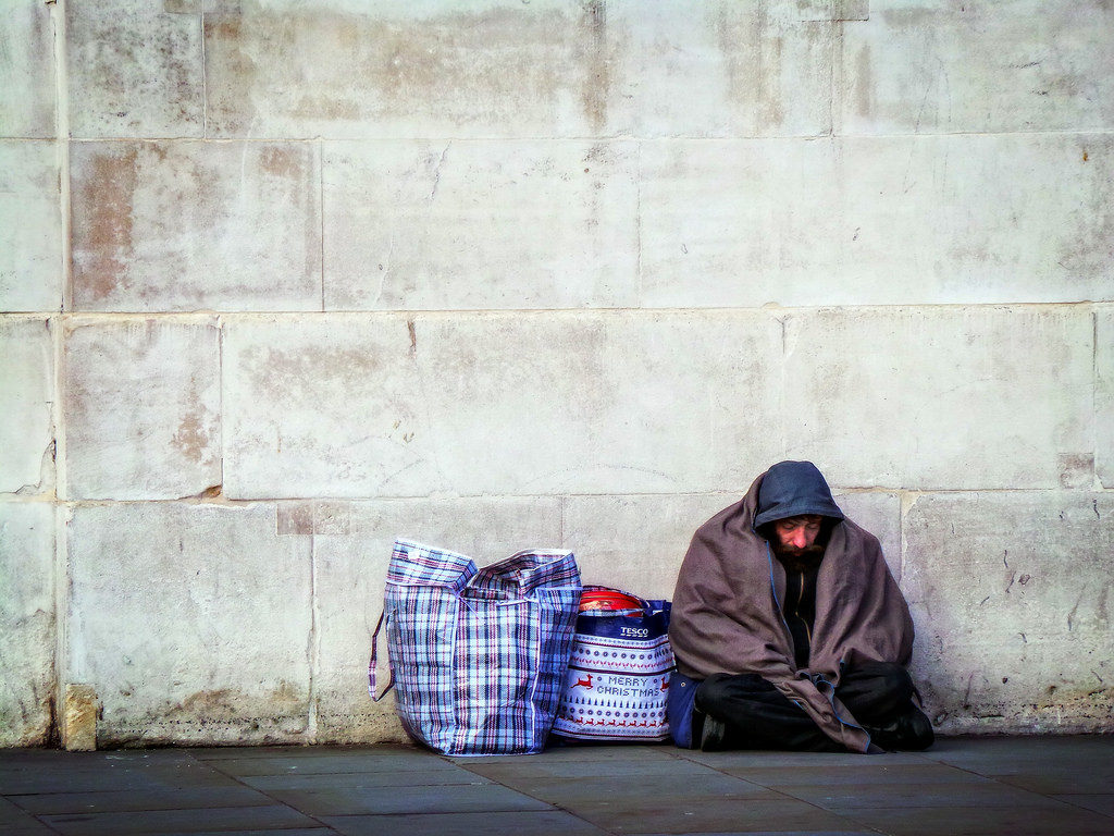A homeless person sheltering under a concrete wall