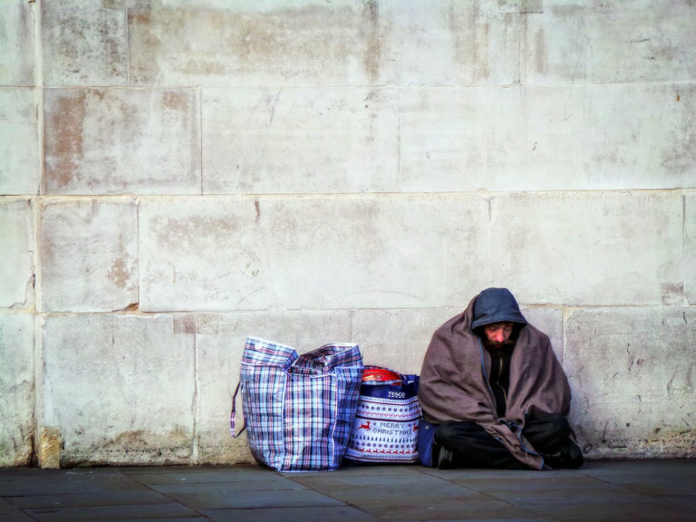 A homeless person sheltering under a concrete wall