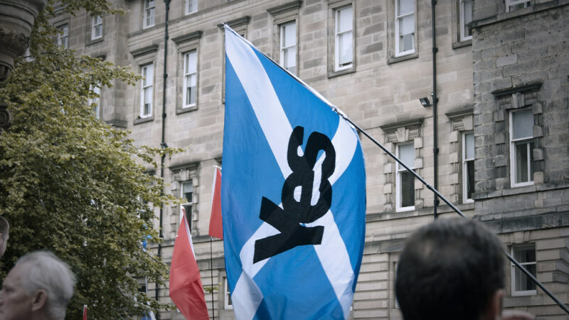 A photo of a Scottish independence protest with a Saltire flagm with the word "yes" imposed on it