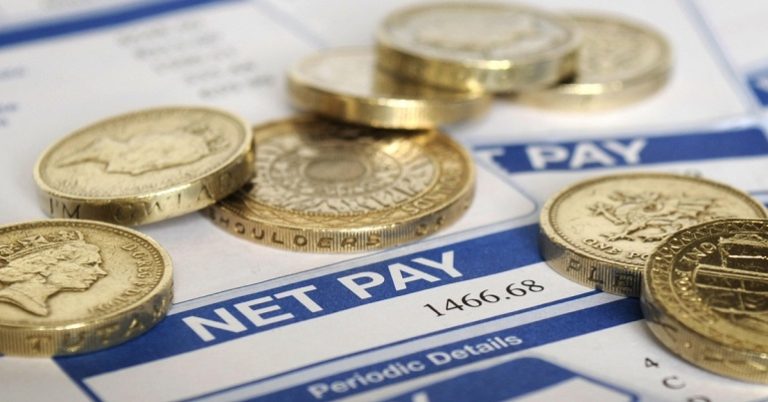 A photo of coins on documents with "Net Pay" written on them