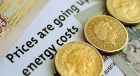 A photo of coins on top of an article explaining that Energy companies are raising prices