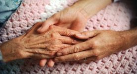 A care worker holding the hand of a patient