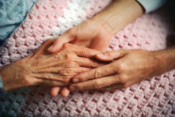A care worker holding the hand of a patient