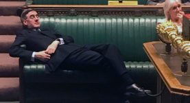 Jacob Rees Mogg lying across the benches in the House of Commons