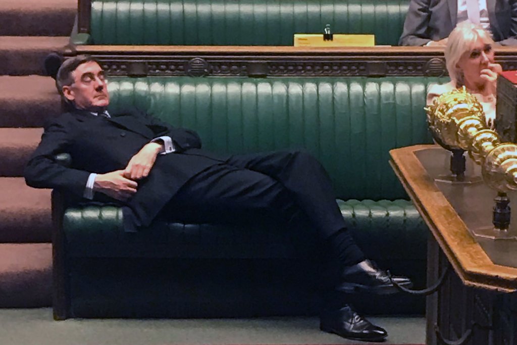 Jacob Rees Mogg lying across the benches in the House of Commons