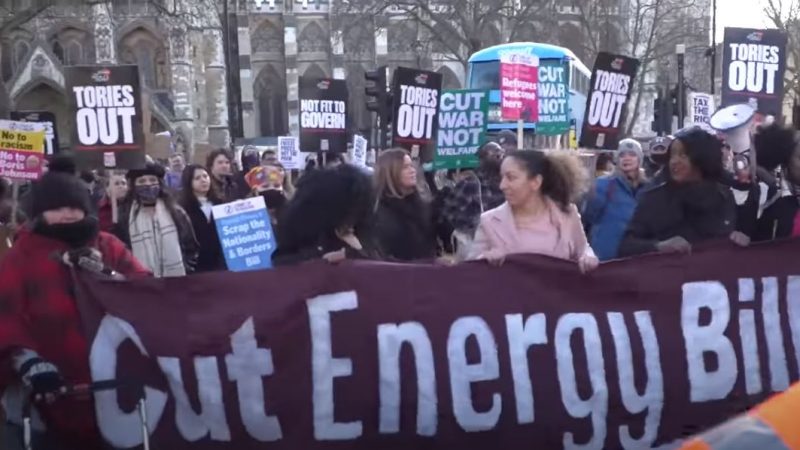 A protest with campaigners holding a banner reading "cut energy bills"