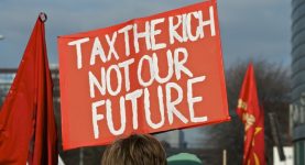 A photo of a placard reading "tax the rich, not our future"
