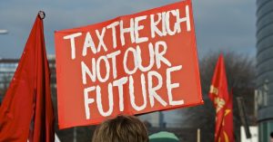 A photo of a placard reading "tax the rich, not our future"