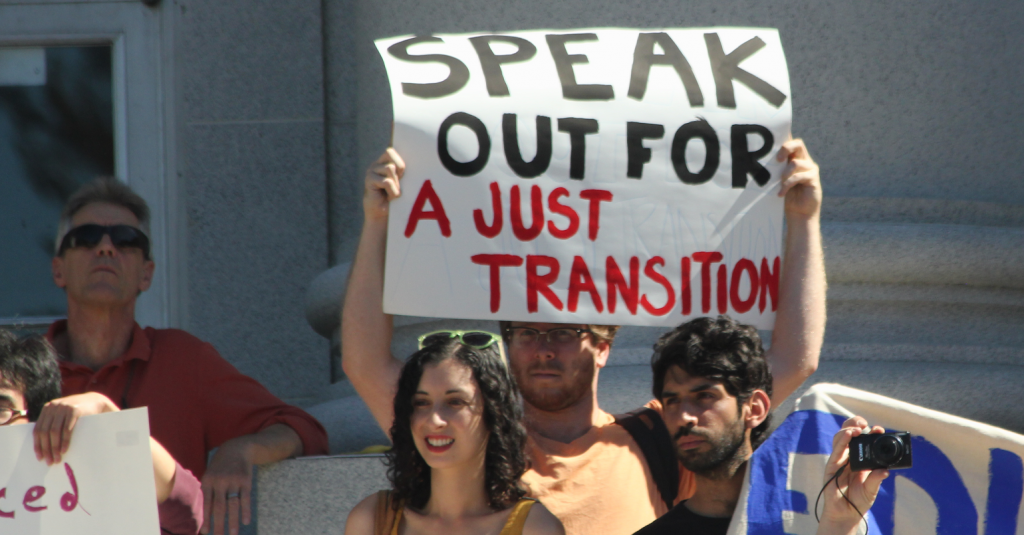A photo of protesters holding a sign reading "Speak out for a just transition"