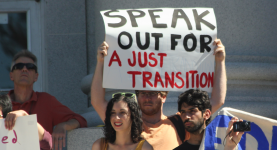 A photo of protesters holding a sign reading "Speak out for a just transition"