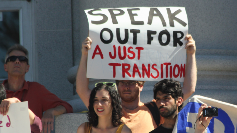 A photo of protesters holding a sign reading "Speak out for a just transition"