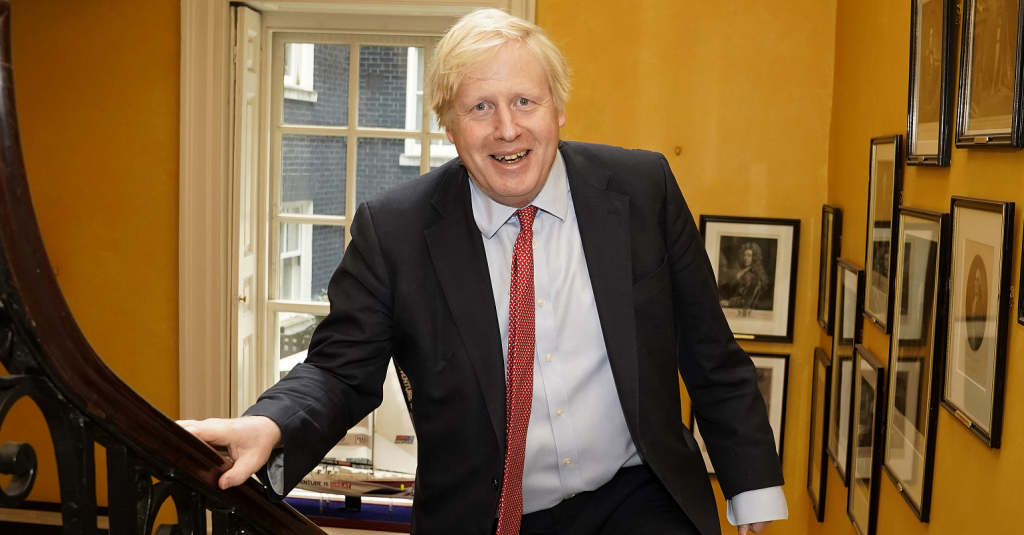 Boris Johnson walking up a set of stairs smiling