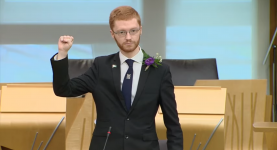 Ross Greer raising a fist at his oath in the Scottish Parliament