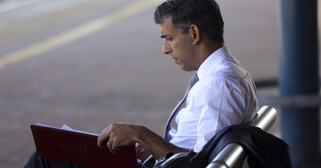 A photo of Rishi Sunak looking at something in a folder