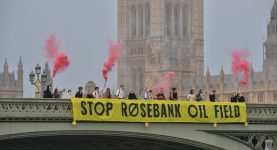 Climate campaigners dropping a banner reading "Stop Rosebank Oil Field" on Westminster Bridge