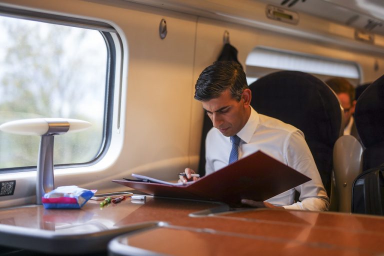 Rishi Sunak reading from a folder on a train