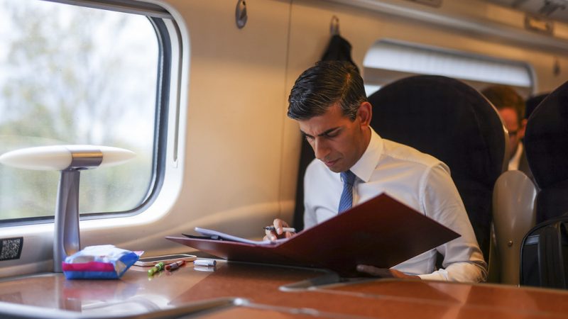 Rishi Sunak reading from a folder on a train