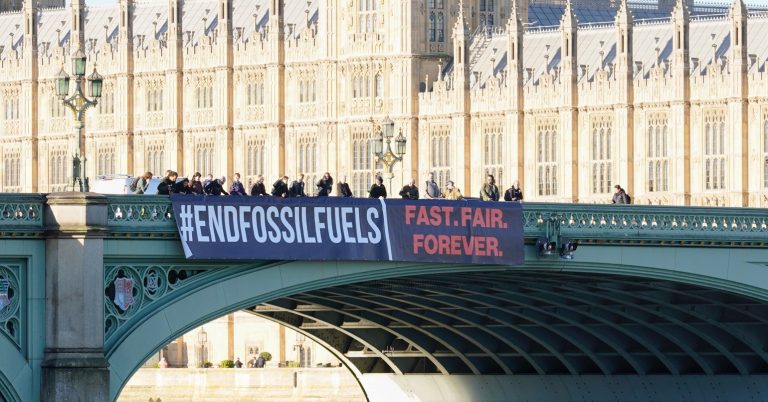 A banner dropped on Westminster Bridge reading "#EndFossilFuels - Fast, fair, forever"