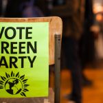 A photo of the back of a chair with a poster attached reading 'vote Green Party'